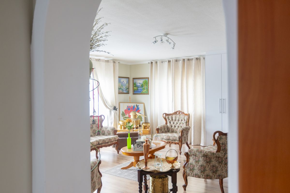 A bright living room featuring laminate flooring, a built-in wardrobe, and a classic archway entrance, offering a comfortable and well-lit living space.