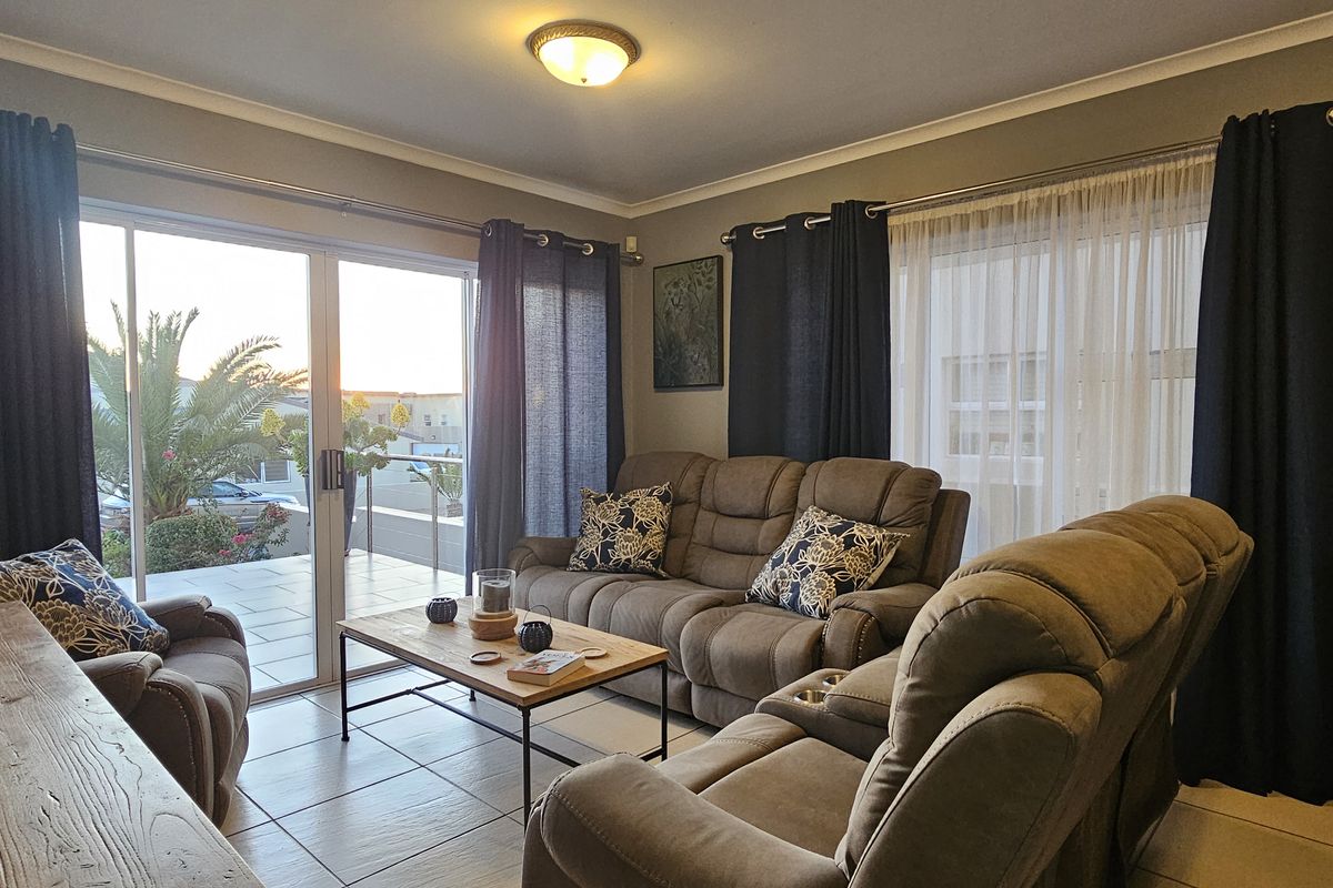 A comfortable living room featuring tiled flooring and large sliding glass doors that provide access to an outdoor patio area.