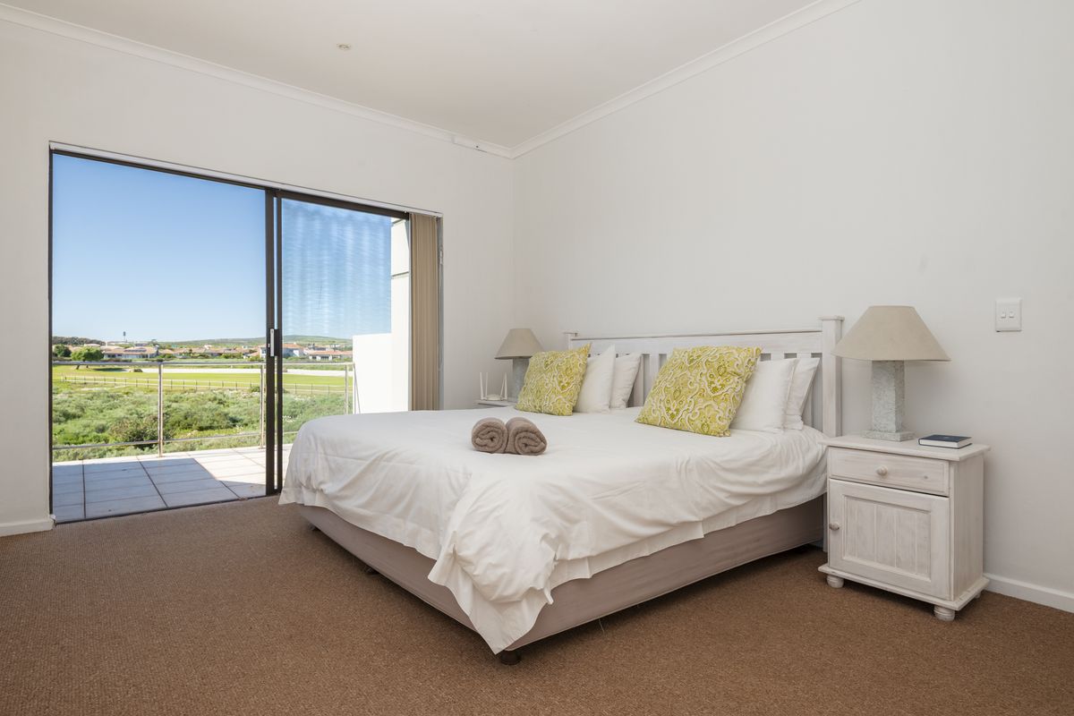 A bright bedroom featuring carpet flooring and a large sliding glass door that opens onto a balcony with scenic views.