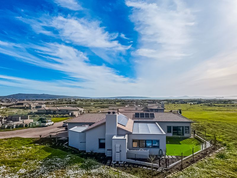 Aerial view of a modern residential property featuring a tiled roof with solar panels, a chimney, and a well-maintained artificial lawn area.