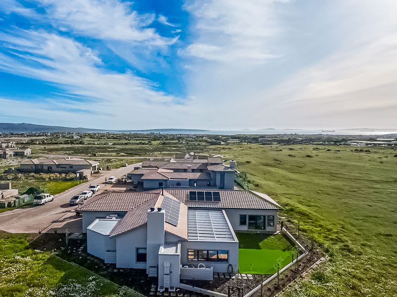 Aerial view of a modern residential property featuring a tiled roof with integrated solar panels, a chimney, and a landscaped garden with artificial lawn.