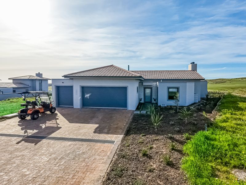 Front elevation of a modern single-story house featuring a double garage, paved driveway, and tiled roof, situated in a landscaped estate setting.