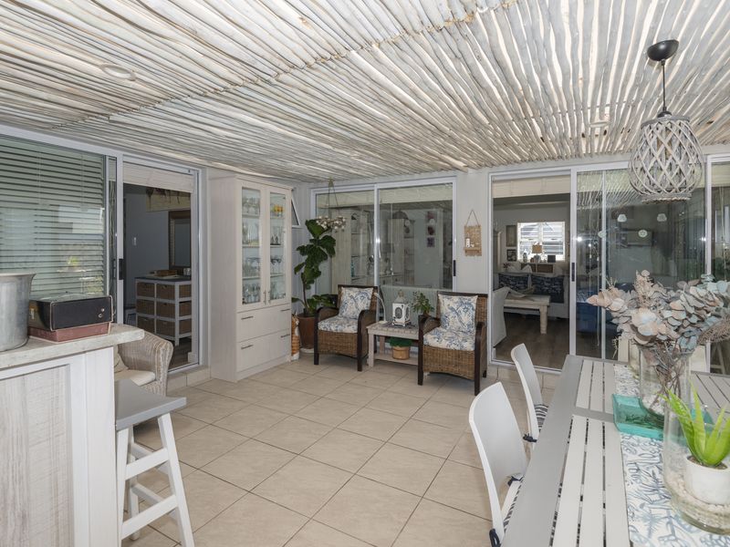 A bright, enclosed patio area featuring tiled flooring, a unique textured stick ceiling, and multiple sliding glass doors providing access to the interior living spaces.