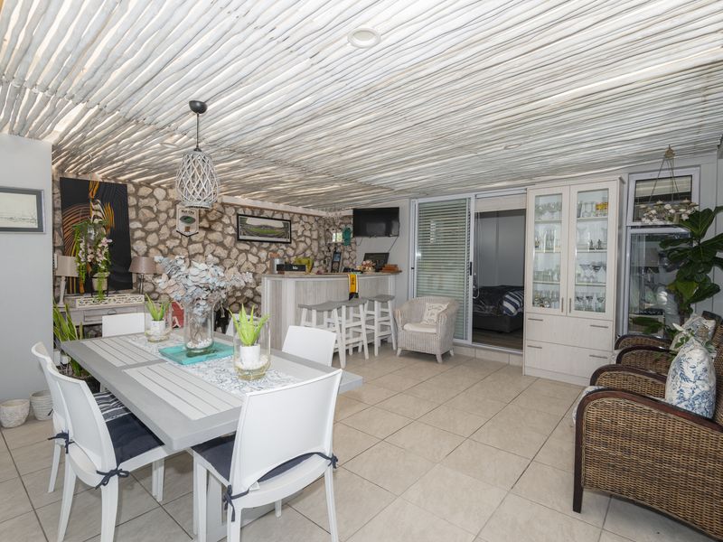 Spacious open-plan living and dining area featuring a unique exposed timber pole ceiling, stone feature wall, and a built-in bar area.