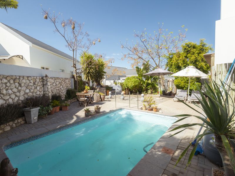 A private outdoor pool area featuring a paved patio surround and a decorative stone boundary wall, perfect for relaxation and outdoor entertaining.