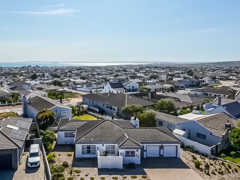 Aerial view of the residential property showing the roof structure, double garage, solar panels, and surrounding neighbourhood with distant coastal views.