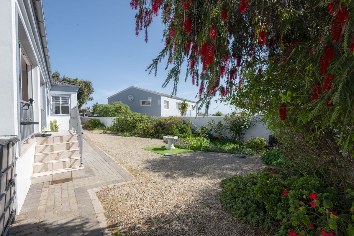 A well-maintained rear garden area featuring a gravel landscape, paved walkway, and an external staircase leading to the main house structure.