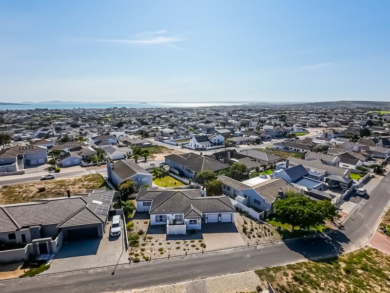 An elevated aerial view of a residential coastal neighborhood, showcasing the property's location, roof structure, and surrounding street layout.