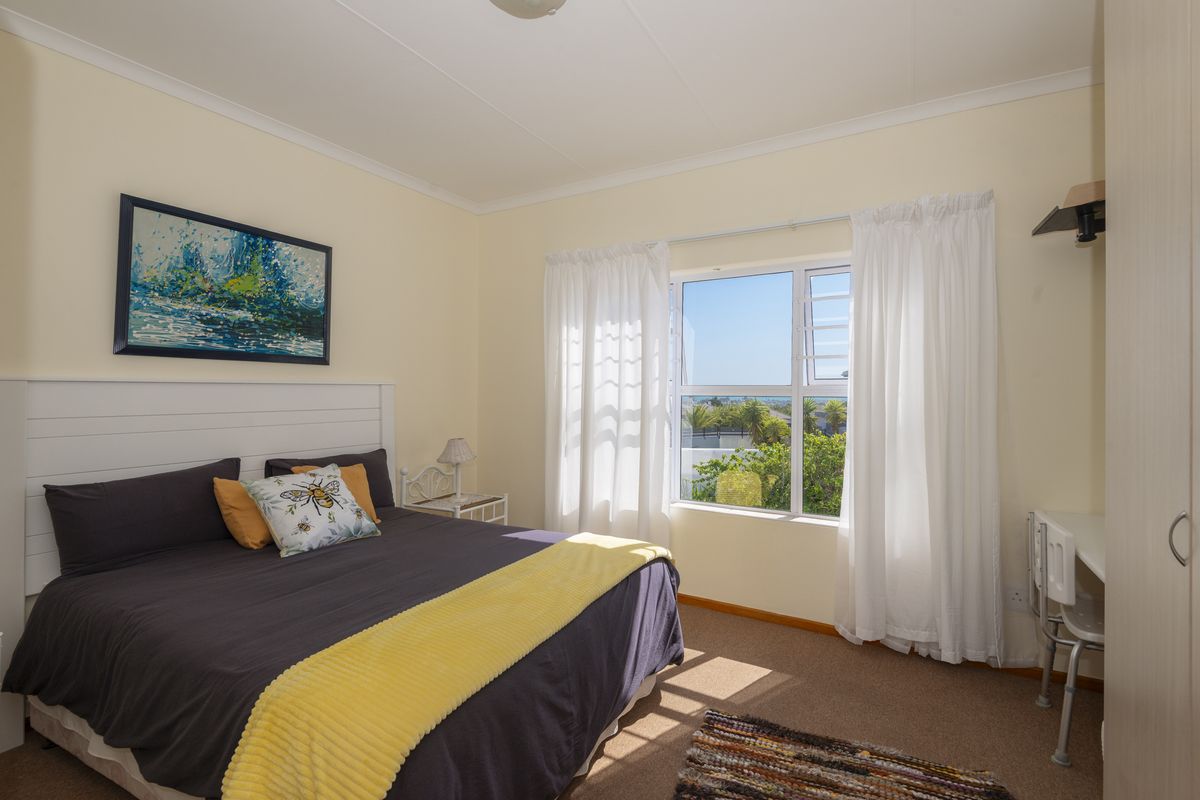 A well-lit bedroom featuring a built-in wardrobe, neutral wall finishes, and a window providing natural light and exterior views.