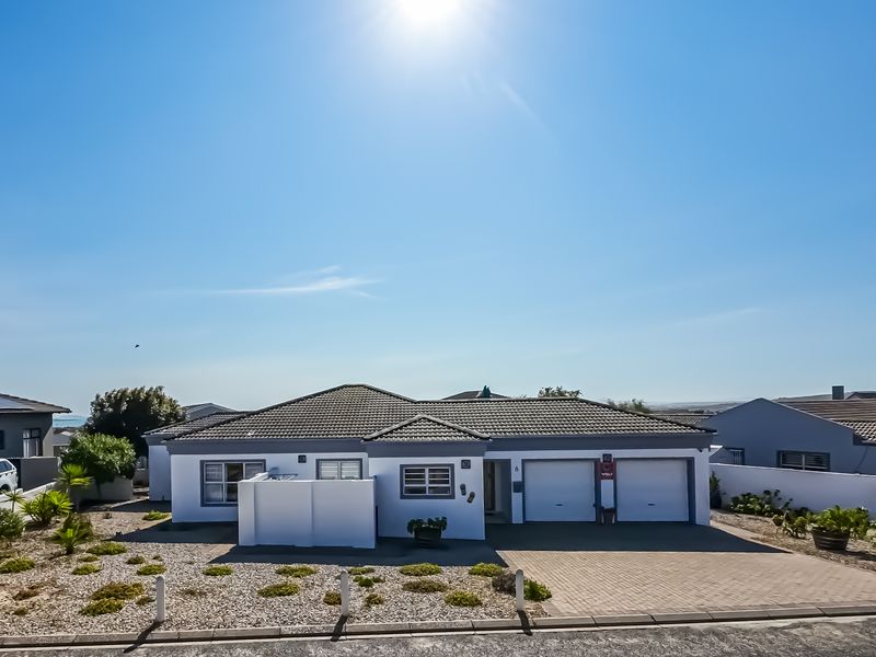 A well-maintained single-story residential property featuring a double garage, paved driveway, and a neat, low-maintenance front garden under a clear sky.