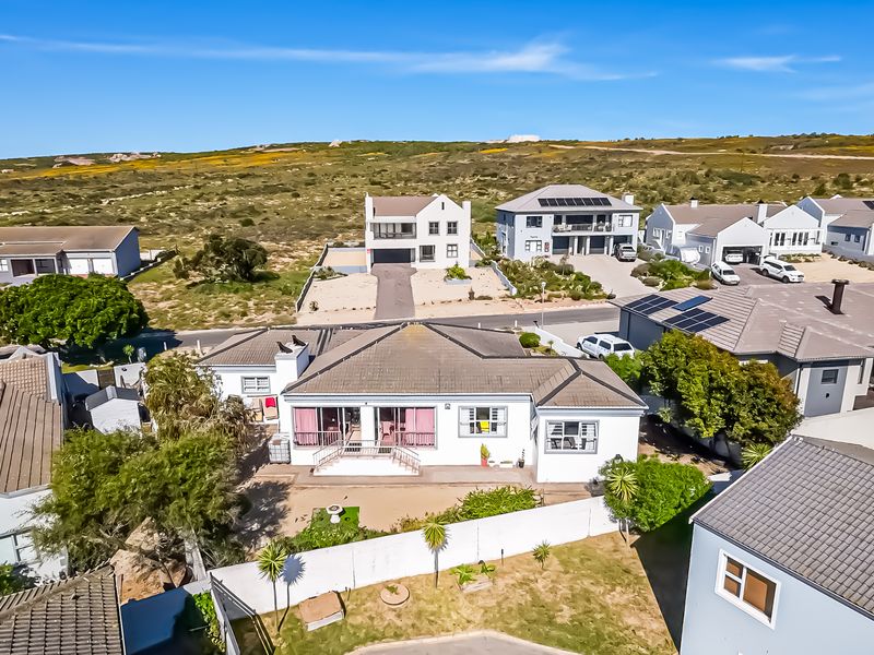 Aerial view of a residential property featuring a tiled roof, solar panels, and a landscaped garden within a suburban coastal estate.