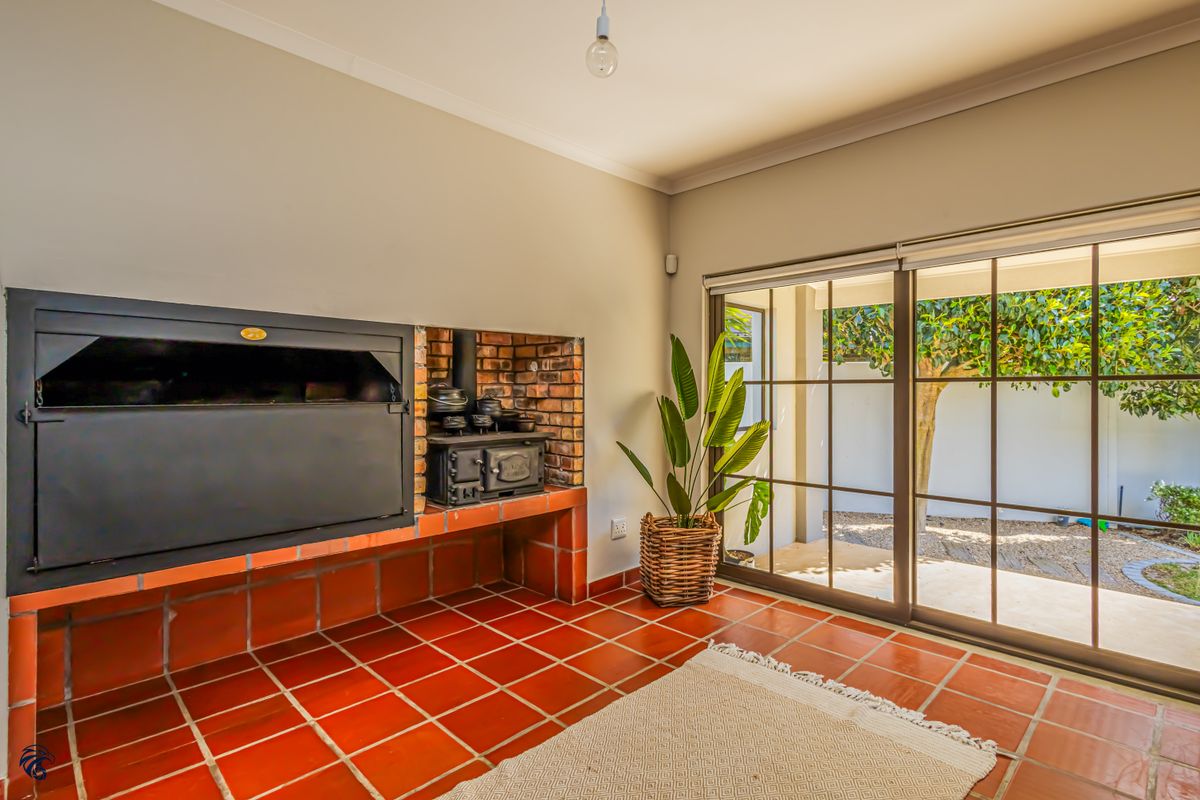 Living area featuring a built-in fireplace with a cast iron stove, terracotta tiled flooring, and large sliding glass doors opening to the garden.