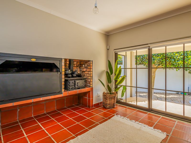 Living area featuring a built-in fireplace with a cast iron stove, terracotta tiled flooring, and large sliding glass doors opening to the garden.