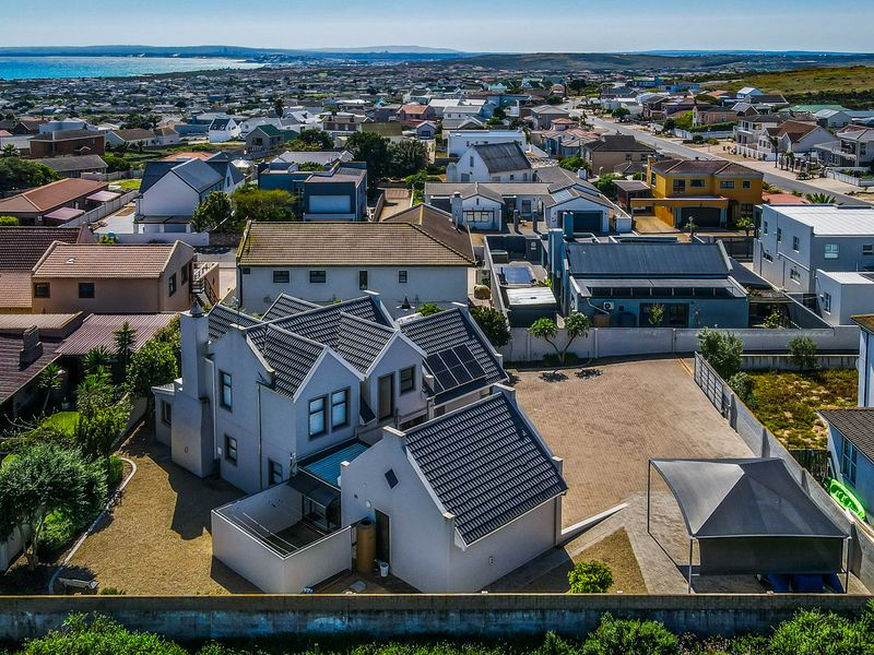 Aerial view of a residential property featuring a tiled roof, solar panels, a paved driveway with a carport, and a secure boundary wall.