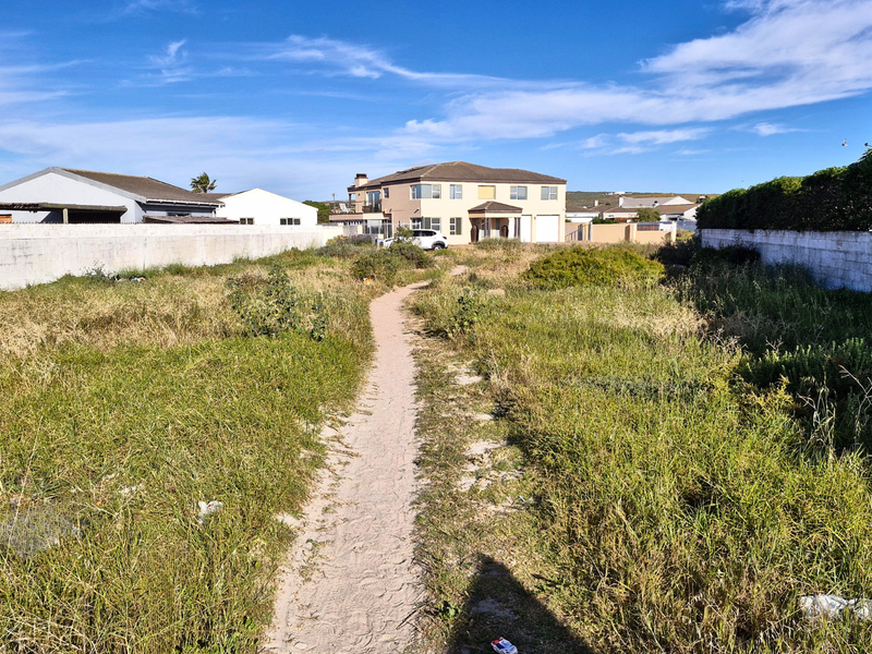 A vacant residential plot featuring boundary walls and overgrown grass, offering a clear space for future development.