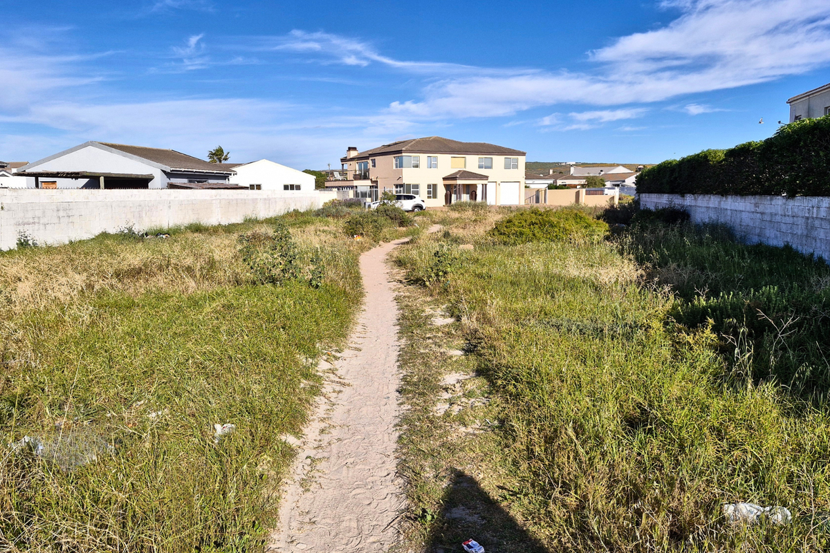 A vacant residential plot featuring boundary walls and overgrown grass, offering a clear space for future development.