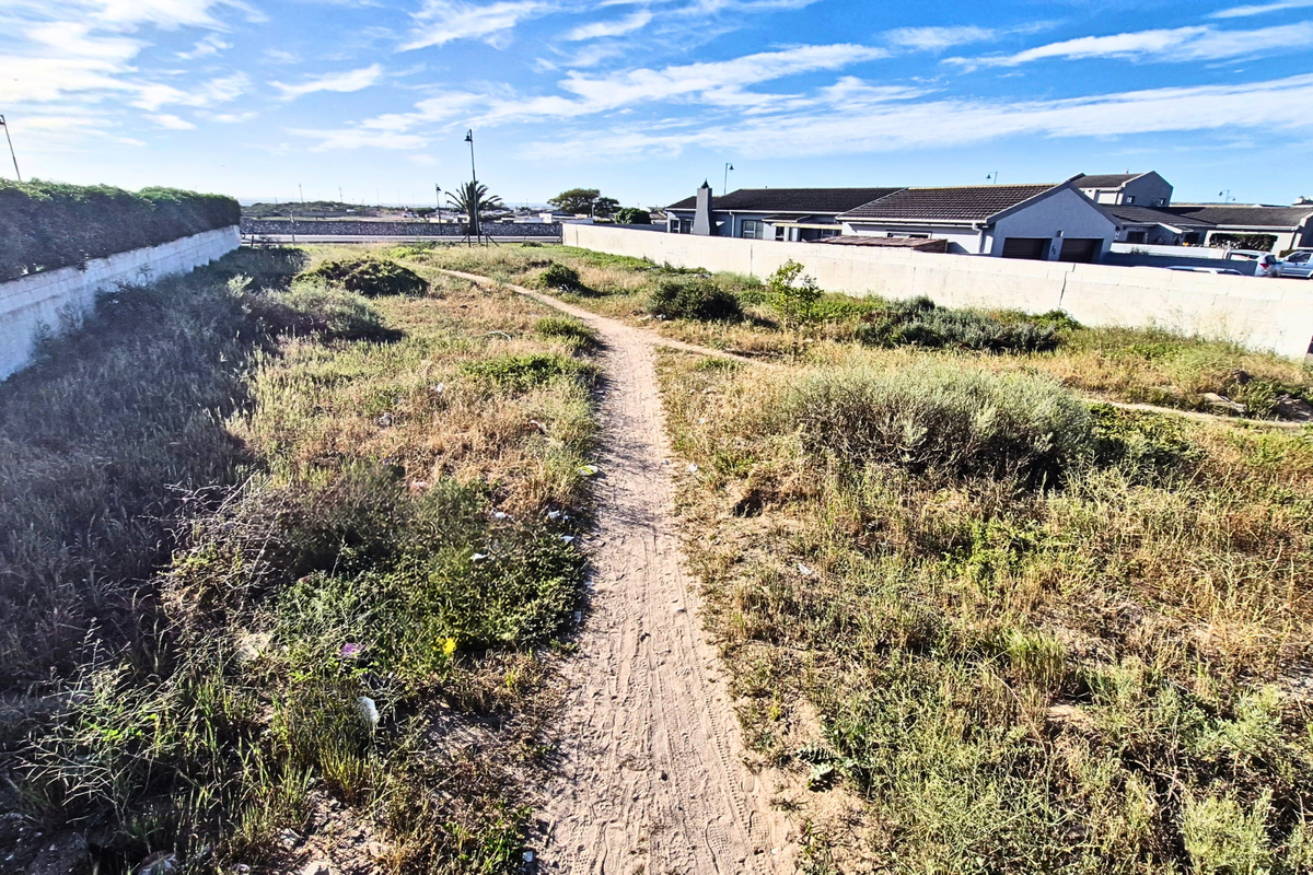 A vacant residential plot featuring perimeter boundary walls and natural vegetation, offering a clear space for future development.