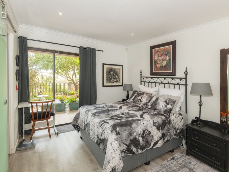 A well-maintained bedroom featuring laminate flooring, recessed lighting, and a sliding glass door providing direct access to the outdoor patio area.