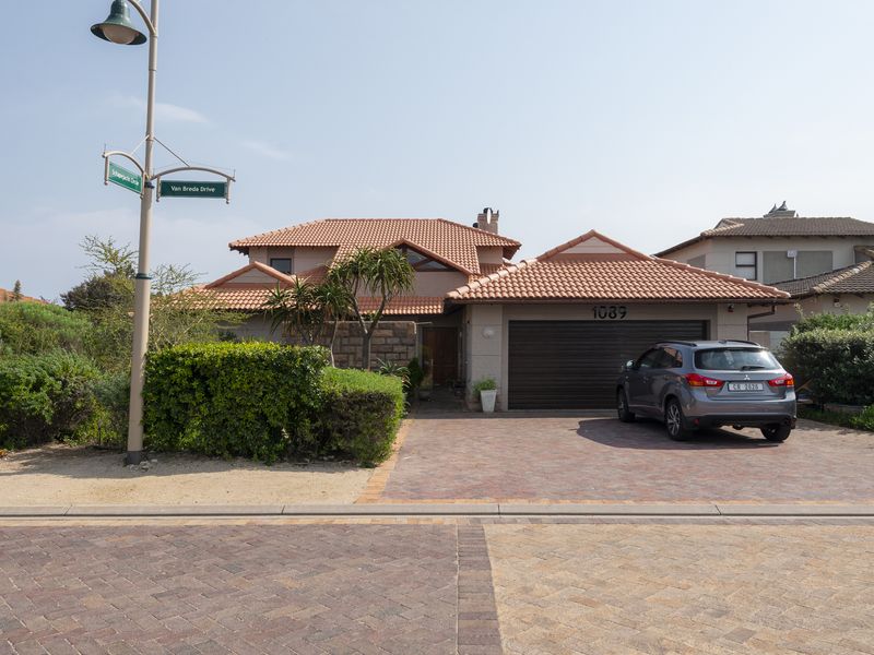 Front elevation of a residential house featuring a tiled roof, stone cladding accents, and a paved driveway leading to a double garage.
