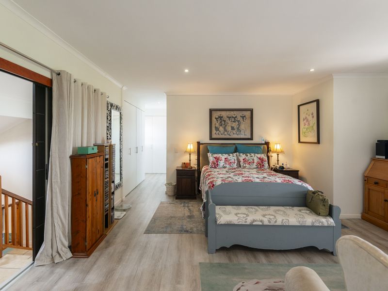 Spacious bedroom featuring light laminate flooring, recessed downlighting, built-in storage, and a sliding glass door providing access to the staircase area.