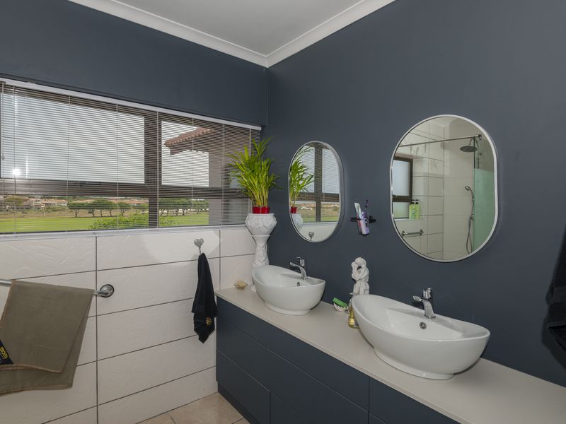 Modern bathroom featuring a double vanity with vessel sinks, chrome fixtures, tiled walls, and a separate shower enclosure with a view.