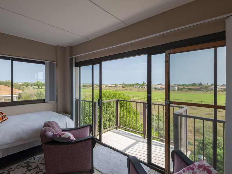 A bedroom featuring large sliding glass doors that open onto a private balcony with scenic views of the surrounding landscape.