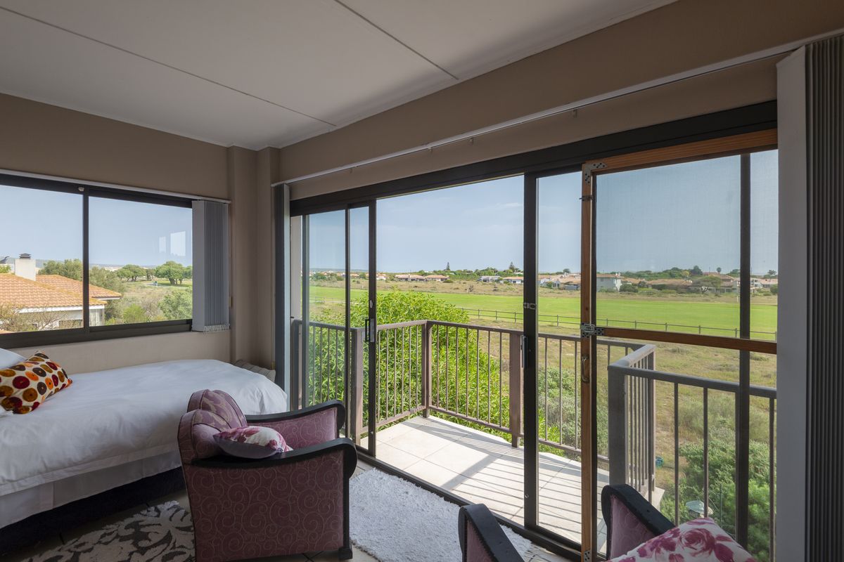 A bedroom featuring large sliding glass doors that open onto a private balcony with scenic views of the surrounding landscape.
