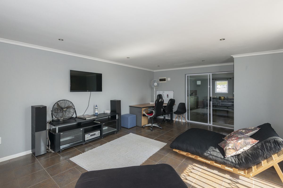 A spacious living area featuring tiled flooring, recessed lighting, and a sliding glass door leading to an adjacent room.