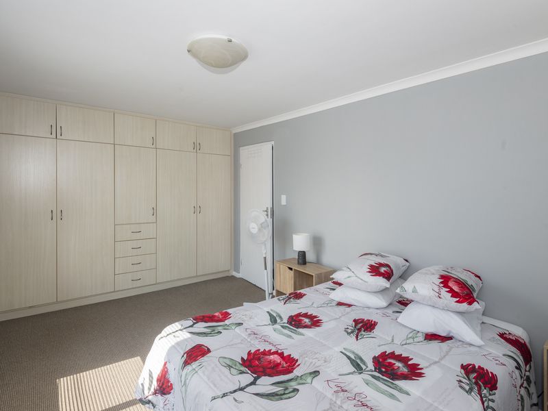 A well-maintained bedroom featuring neutral grey walls, carpeted flooring, and extensive built-in cabinetry for storage.
