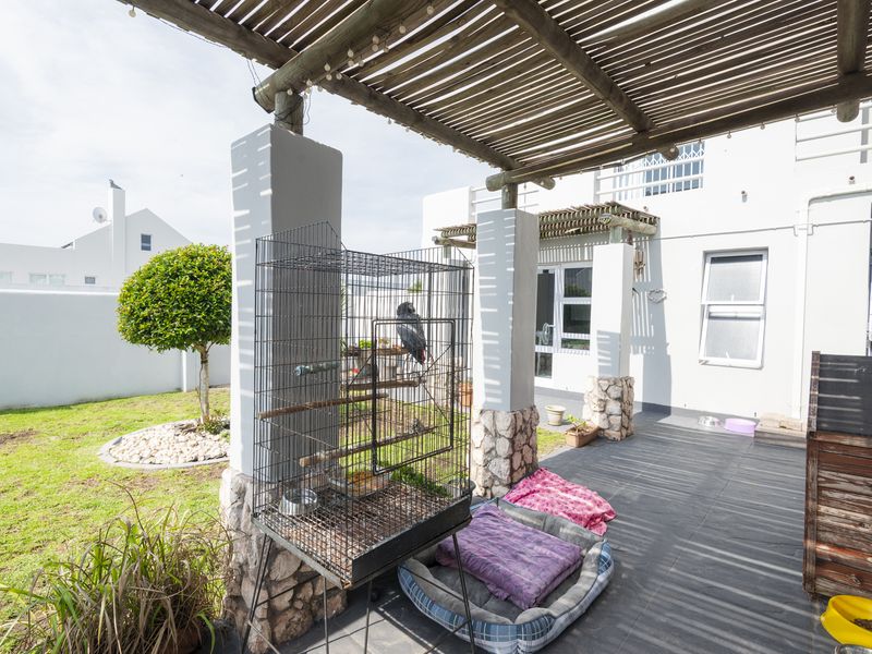 A covered patio area featuring a timber pergola, stone-clad pillars, and tiled flooring, providing a seamless transition to the rear garden.