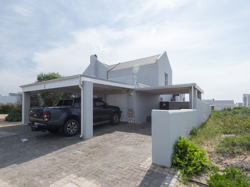 Front exterior view of the property featuring a paved driveway, covered carport, and a secure garage entrance.