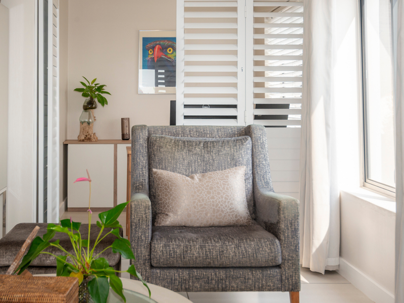 A bright and well-maintained living area featuring neutral tiled flooring and white plantation shutters, creating a clean and inviting atmosphere.