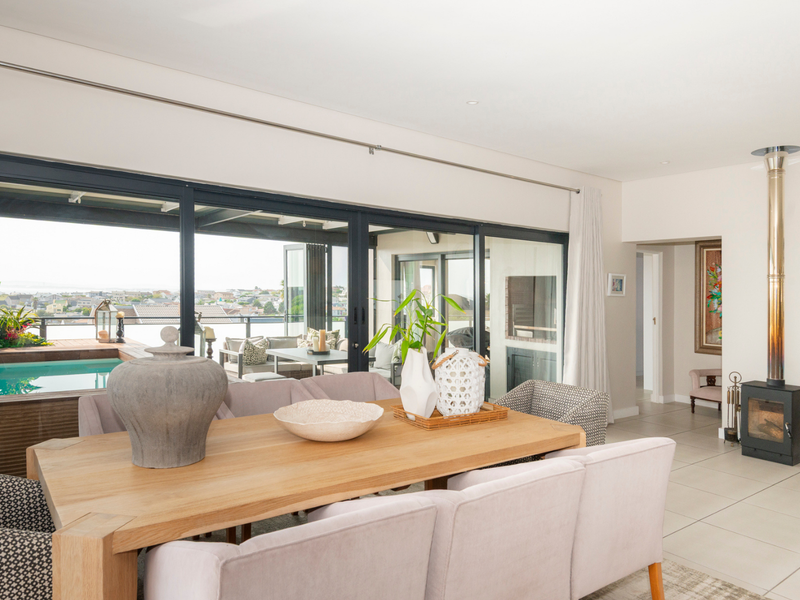 Bright open-plan living and dining area featuring large sliding glass doors, tiled flooring, and a modern freestanding fireplace, with seamless access to the outdoor patio.