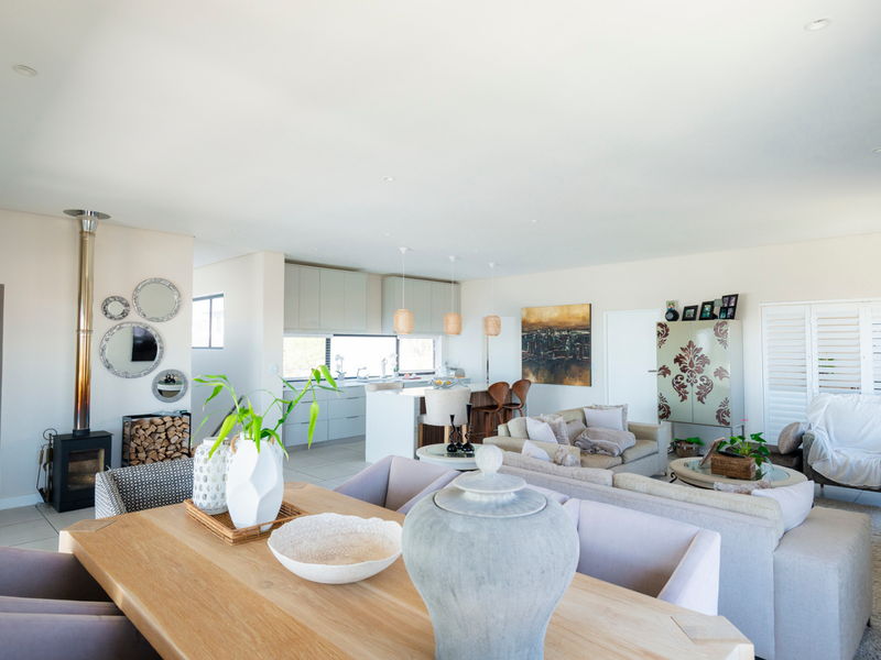 Spacious open-plan living area featuring a modern kitchen with island, dining space, and a cozy freestanding fireplace, finished with neutral tones and tiled flooring.