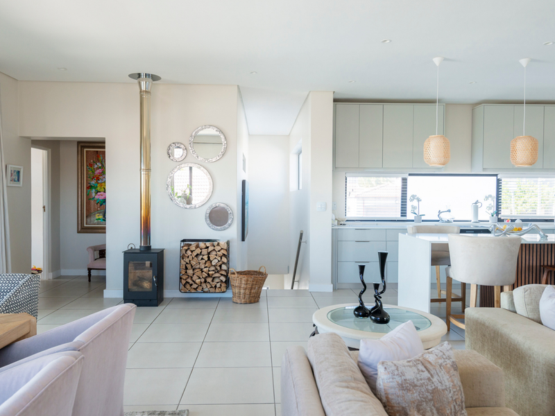 Spacious open-plan living and kitchen area featuring a modern freestanding fireplace, sleek cabinetry, kitchen island, and large sliding doors leading to the exterior.