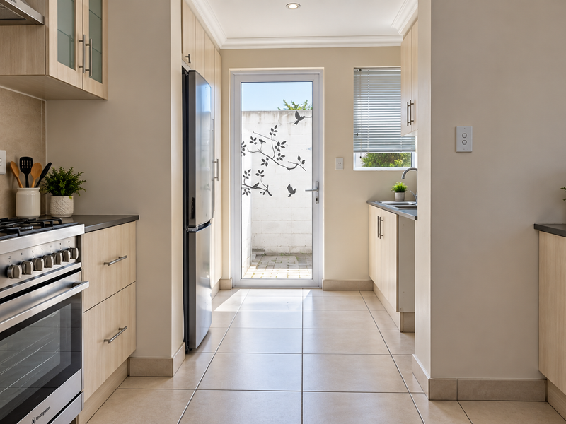 Modern kitchen featuring light wood cabinetry, mosaic tile backsplash, stainless steel appliances, and direct access to a private rear courtyard.