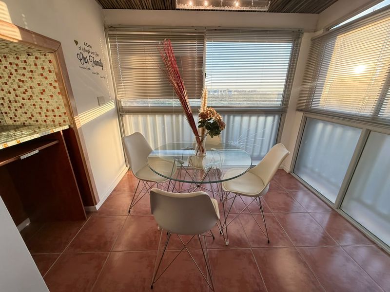Enclosed balcony area featuring tiled flooring, sliding glass doors with venetian blinds, and a mosaic tile accent wall.