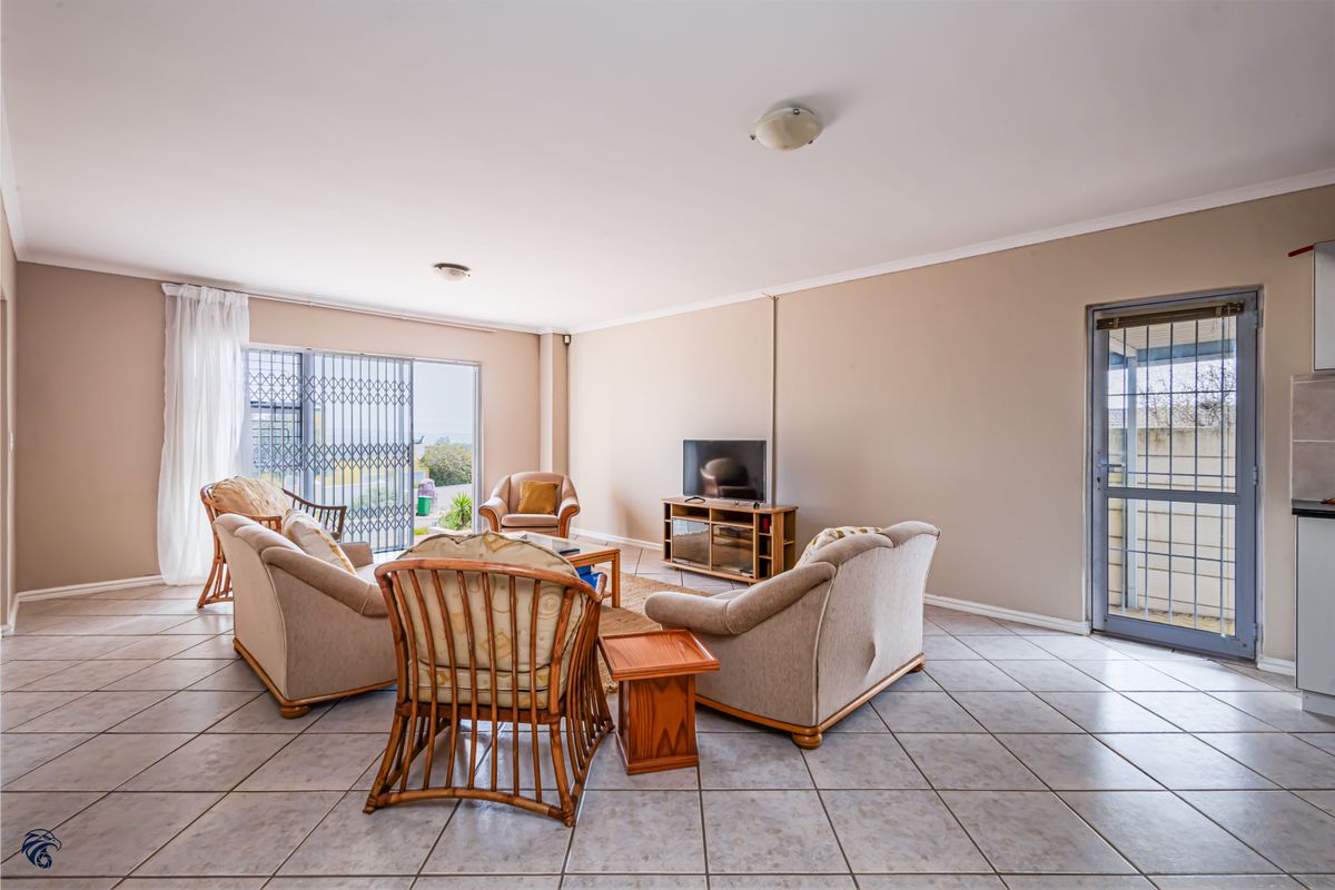 Spacious living room featuring neutral ceramic floor tiles, coved ceilings, and a sliding glass door with security gate providing access to the exterior.