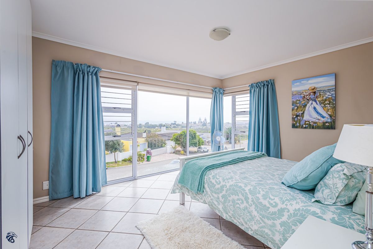 Bright bedroom featuring tiled flooring, built-in wardrobe, and large windows offering expansive neighbourhood views.