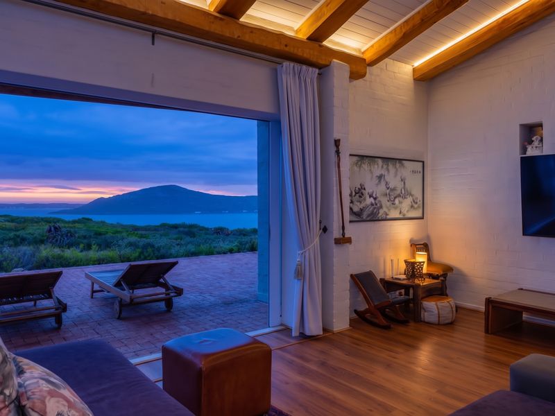 A beautifully appointed living room featuring exposed timber beams, recessed lighting, and seamless indoor-outdoor flow to a patio with stunning coastal and mountain views.
