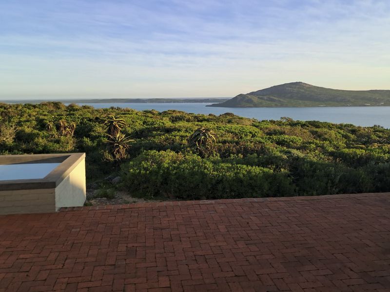 A scenic outdoor view featuring a brick-paved patio, a small plunge pool, and expansive coastal landscape views.