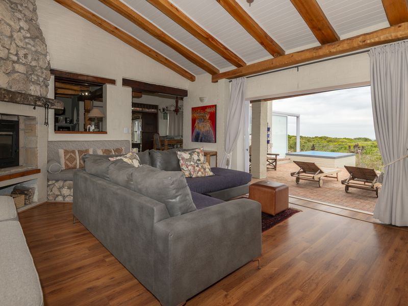 Spacious living room featuring a stone fireplace, exposed timber beams, and large sliding doors opening onto a patio with outdoor views.
