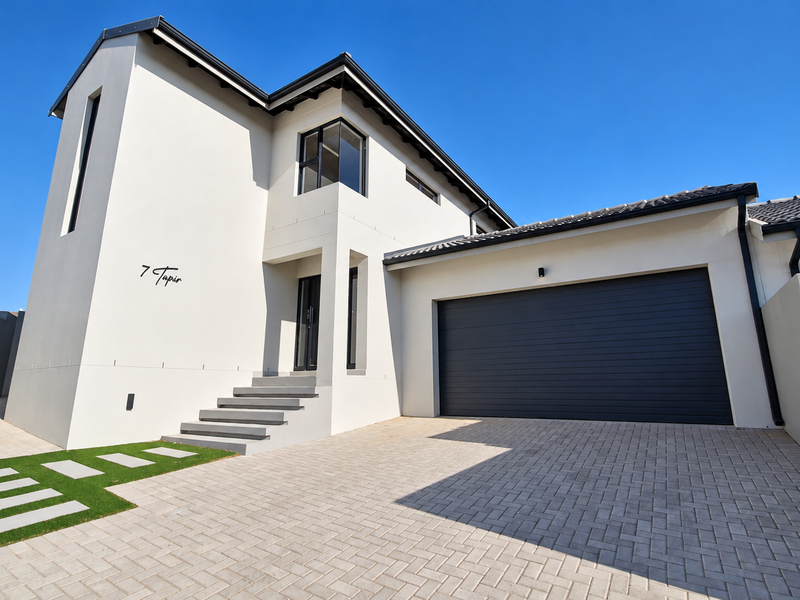 Modern double-storey residential home featuring a clean plastered facade, paved driveway, and a spacious double garage.