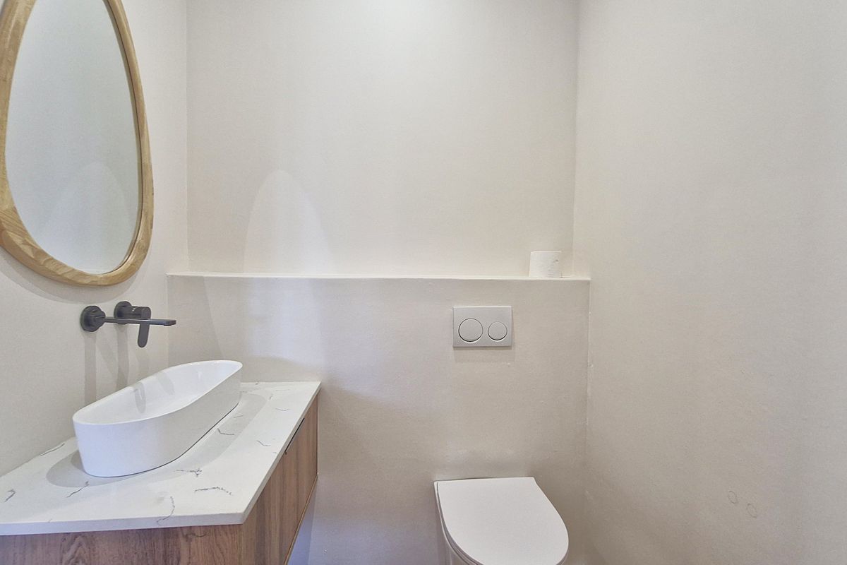 Modern guest bathroom featuring a wall-mounted basin, stone-topped vanity cabinet, and a concealed cistern toilet with a minimalist flush plate.