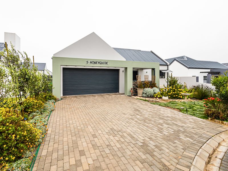 Front elevation of a modern house featuring a paved driveway, automated garage door, and well-maintained landscaped garden.