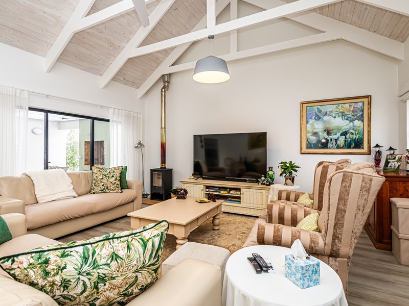 Spacious living room featuring a high vaulted ceiling with exposed beams, a wood-burning fireplace, and large sliding glass doors leading to the patio.