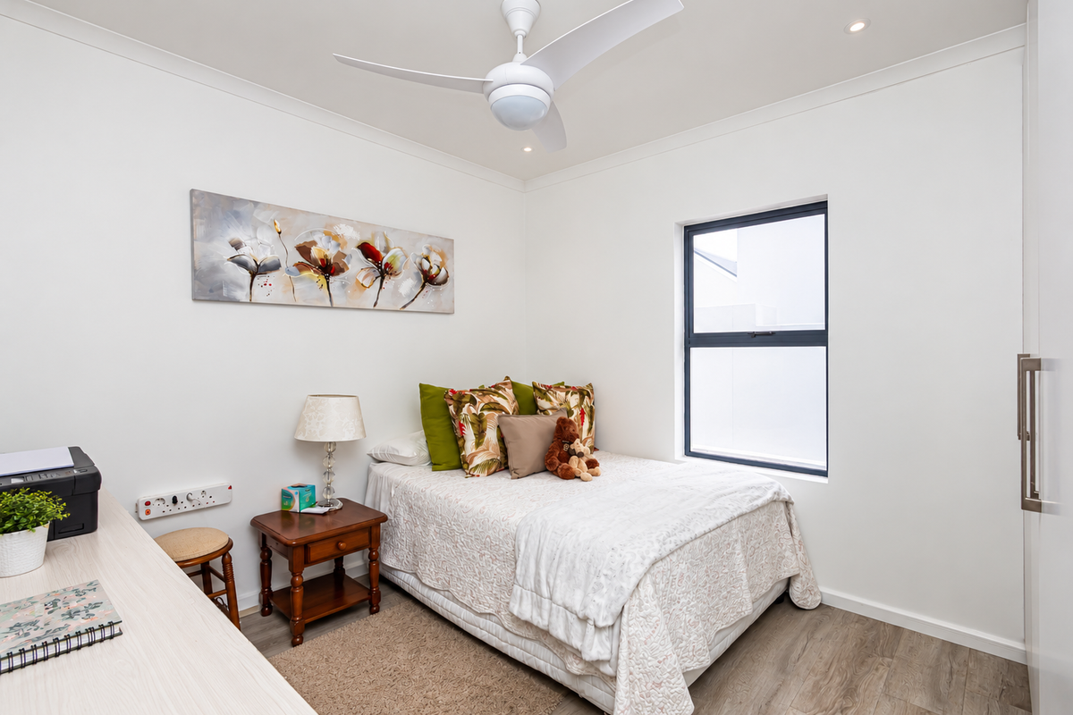 A well-maintained bedroom featuring a ceiling fan, recessed lighting, laminate flooring, and a built-in wardrobe with a modern finish.