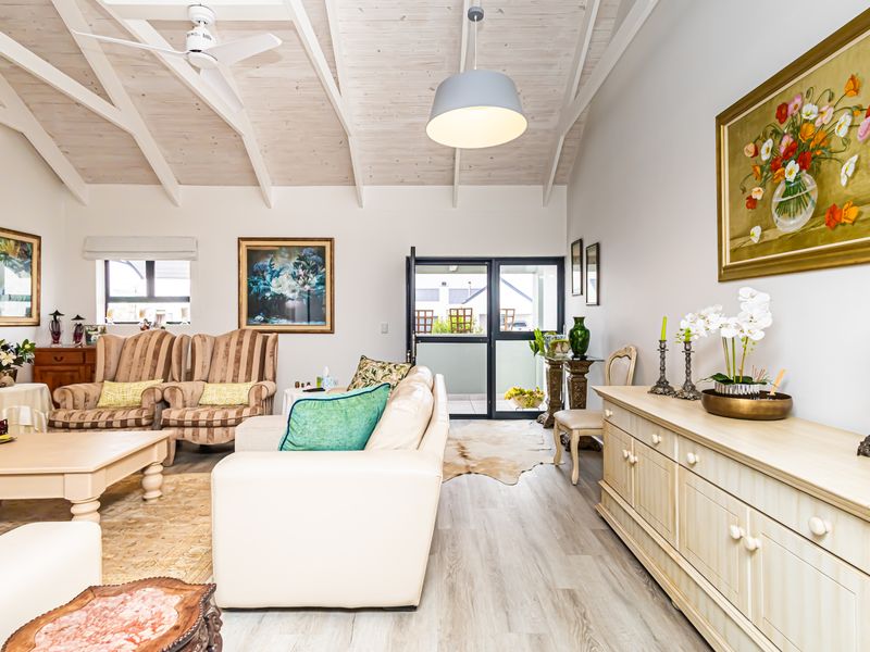 Spacious living room featuring a high vaulted timber ceiling, ceiling fan, and light-toned laminate flooring with direct access to an outdoor area.