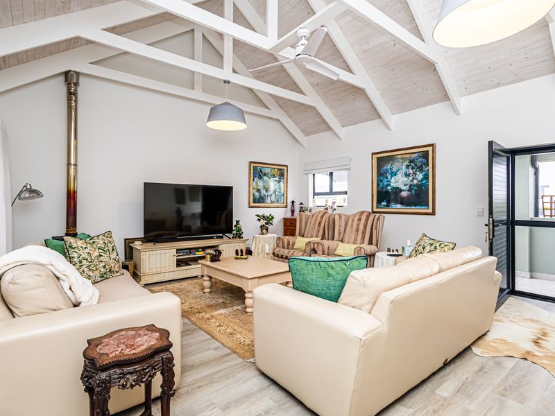 Spacious living room featuring a high vaulted ceiling with exposed timber beams, a freestanding fireplace, and direct access to an outdoor area.