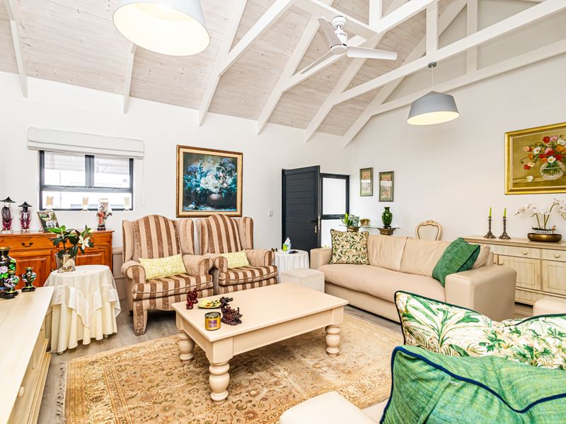 Spacious living room featuring a high vaulted ceiling with exposed white timber beams, ceiling fan, and neutral finishes.